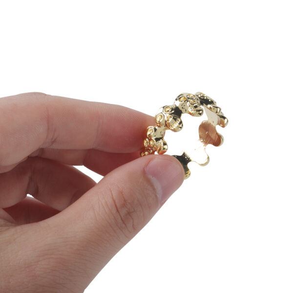 Banoch eikelring doodskop goud cockring geklemd tussen 2 vingers